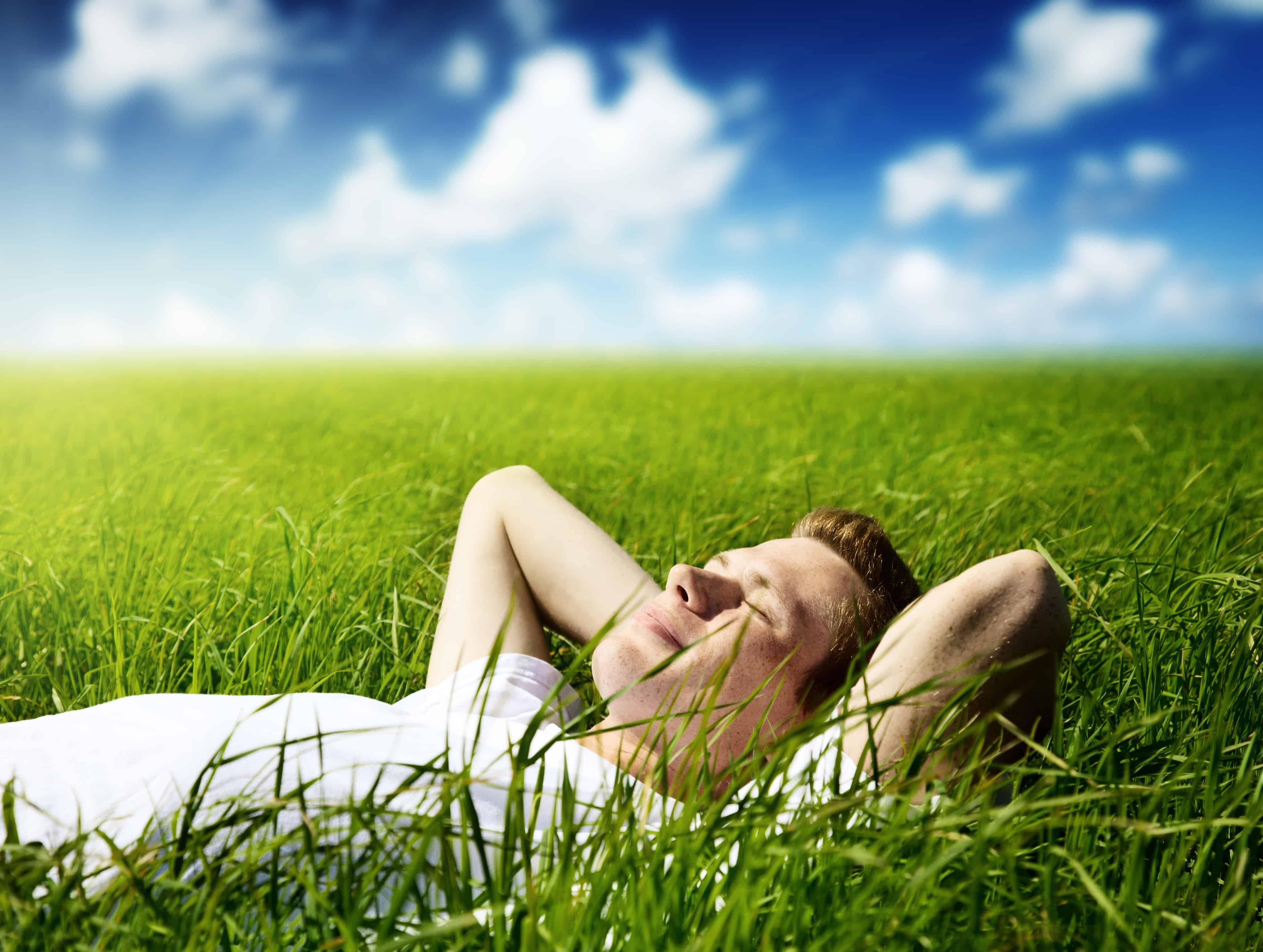 Потом спокойный. Человек лежит на траве. Парень лежит на траве. Мужчина отдыхает на траве. Расслабление на природе.